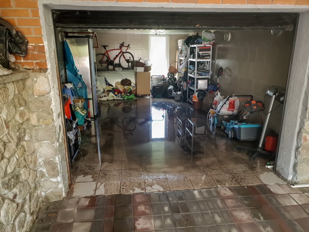 Image of flooded garage after heavy rain. Wet floor and floating thing in house after flood